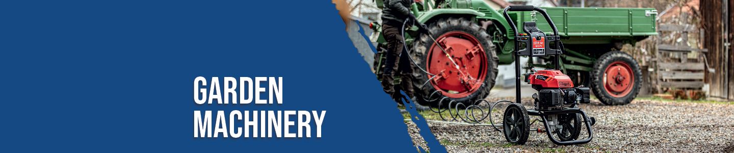 A Scheppach garden machinery with a red engine and black frame. In the background, there is a green tractor with a trailer.