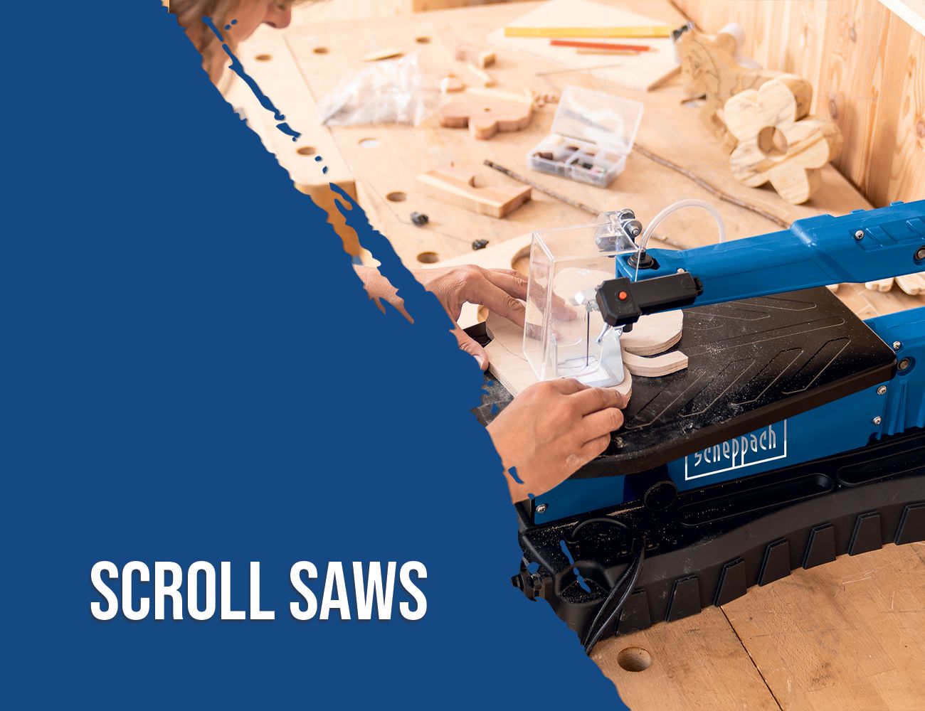 A Scheppach scroll saw with a transparent dust bag attached to the machine. In the background, a workbench with various tools and pieces of wood is visible.