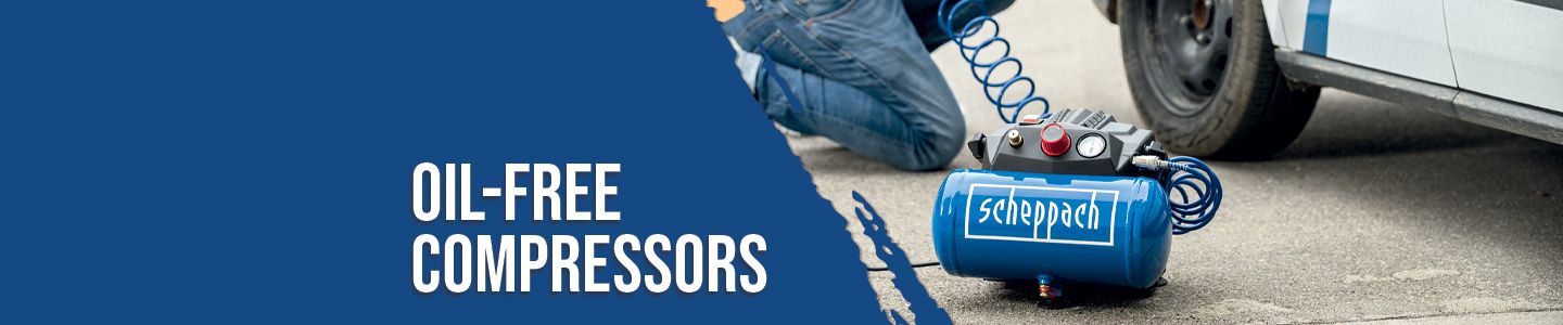 A Scheppach oil-free compressor next to a car. A mechanic is working on the underside of the car.