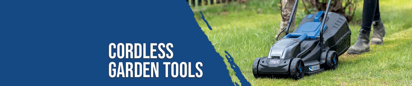 A Scheppach cordless lawnmower on a green lawn. A person stands next to it, holding the handle of the device. A garden fence is visible in the background.