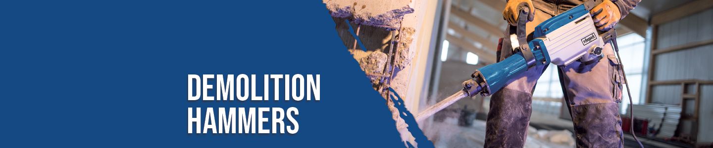 A worker using a Scheppach demolition hammer in a workshop. The hammer is directed at a wall and used for demolition work.