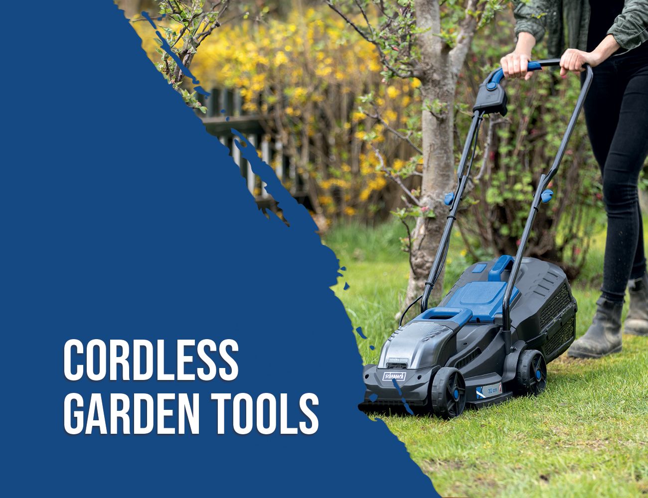 A Scheppach cordless garden tool standing on a lawn. A person is holding the handle and pushing it across the grass. Trees and bushes are visible in the background.