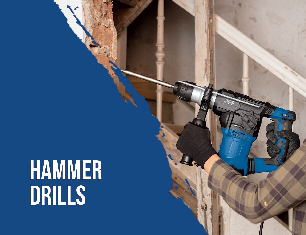 A Scheppach hammer drill in use, drilling a hole into a wall. The user is wearing work gloves and a plaid jacket.
