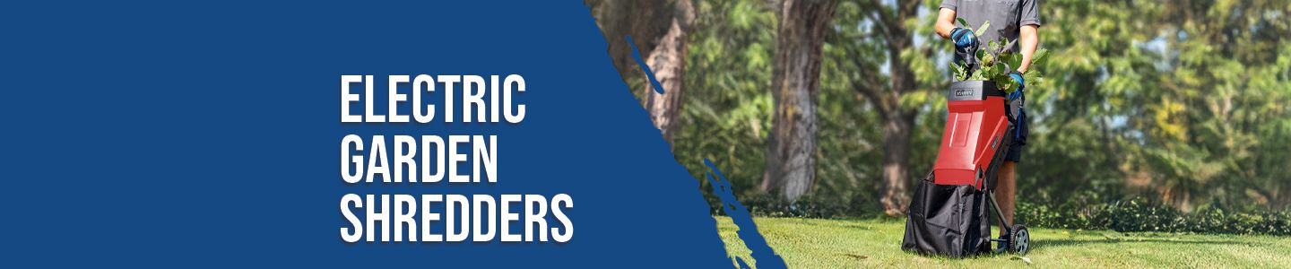 A man operates an electric garden shredder by Scheppach in the garden. The shredder processes branches and twigs. Trees and bushes are visible in the background.