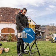 Man operating a Scheppach rocker log saw outdoors