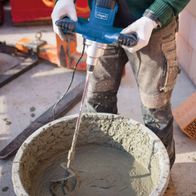 Hand mixer with mortar attachment mixing mortar in a bucket