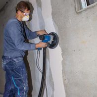 Person sanding wall surface with Scheppach wall and ceiling sander (DS200) inside