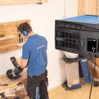 Scheppach HDA-14 air purifier with remote control, suspended in workshop setting