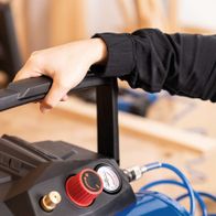 Hand-operated compressor with pressure control and tank for workshop use