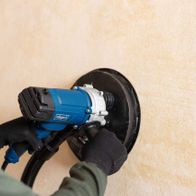 Scheppach wall and ceiling sander with attached grinding disc on wall