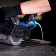 Scheppach metal wire brush with handle, close-up of operation on a workpiece