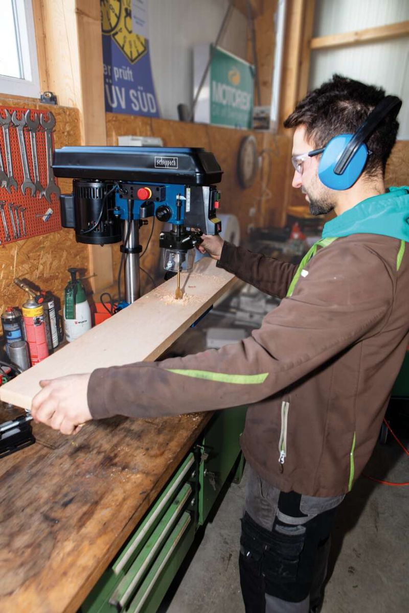 Person operating a Scheppach bench pillar drill with laser guidance in a workshop setting
