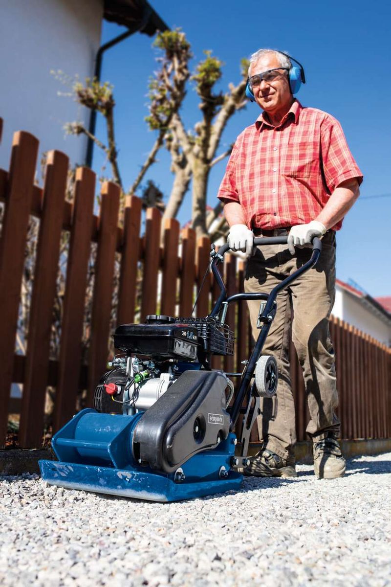 Man operating a Scheppach vibrating plate compactor outdoors