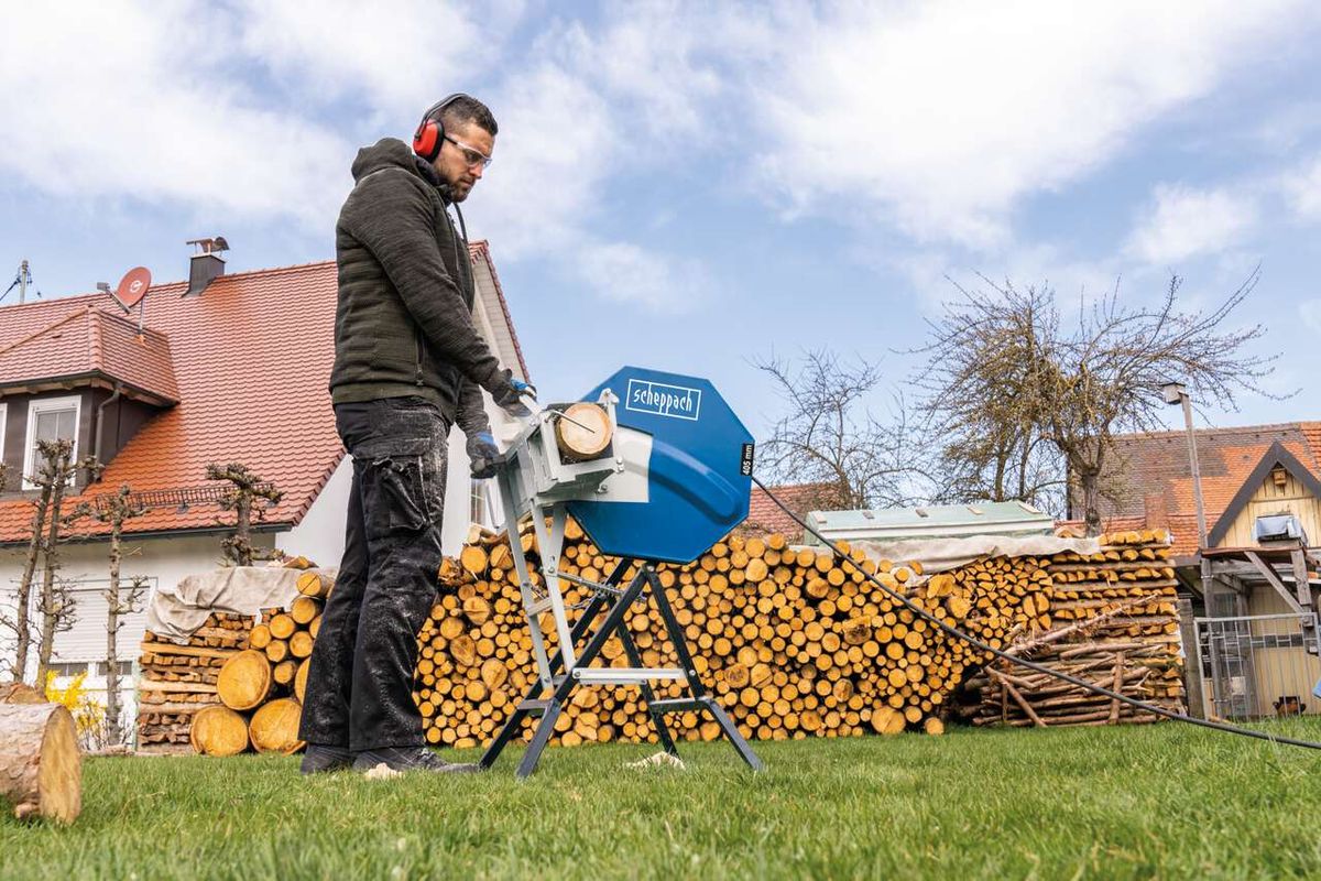Scheppach rocking log saw in use with wood stack and operator