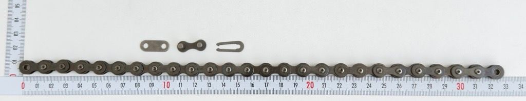 A single roller chain, 26 links 8187, with a closure, by Scheppach. The chain is placed on a ruler and photographed from the front.