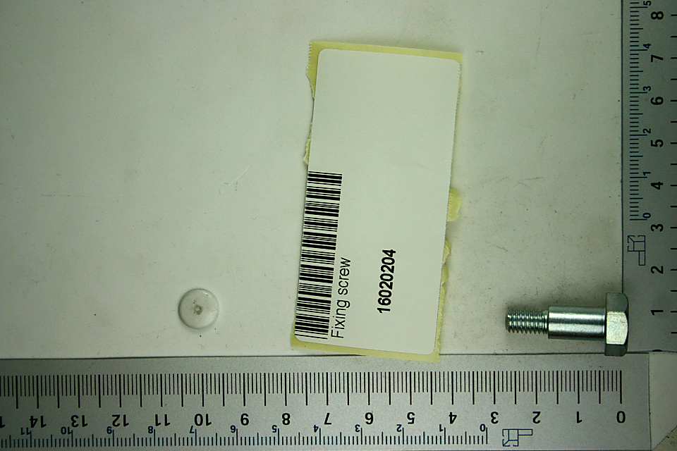 Fixing screw, photographed from above, with product label and ruler in the background.
