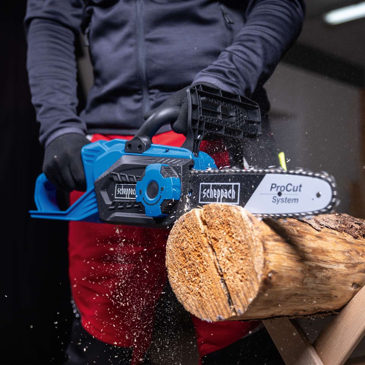 Scheppach cordless chainsaw in action cutting wood, close-up showing battery and blade