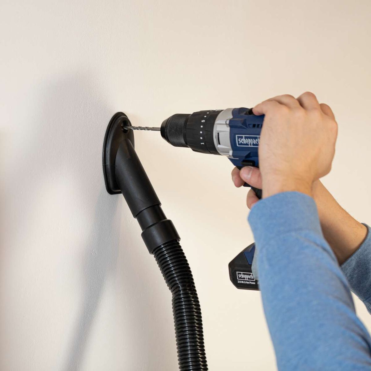 Scheppach drill and suction adapter attached to wall with hose connected