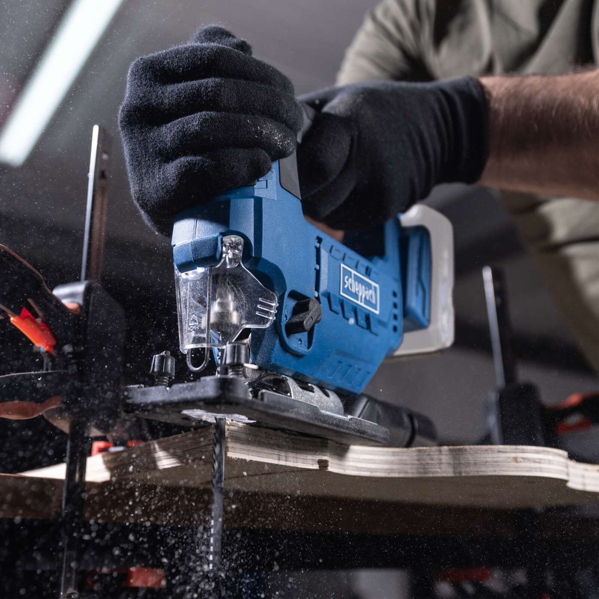 Cordless jigsaw with tool in use, close-up of cutting blade assembly