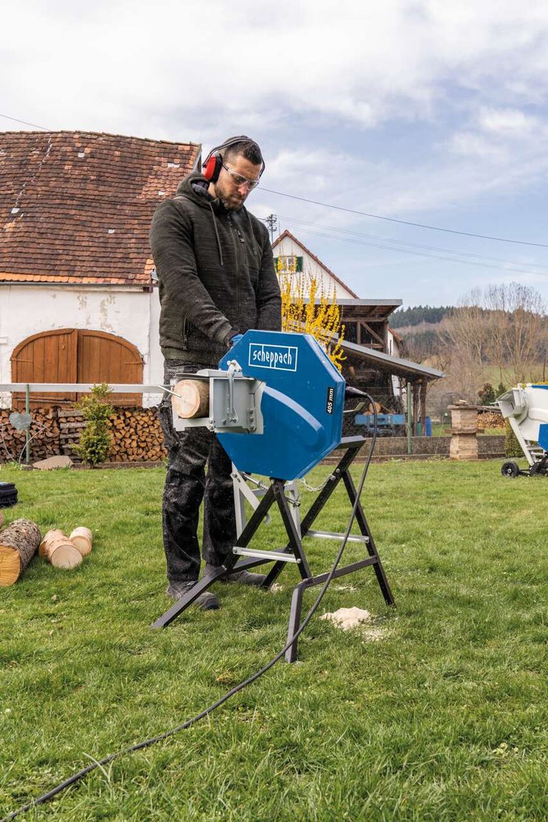 Man operating a Scheppach rocker log saw outdoors