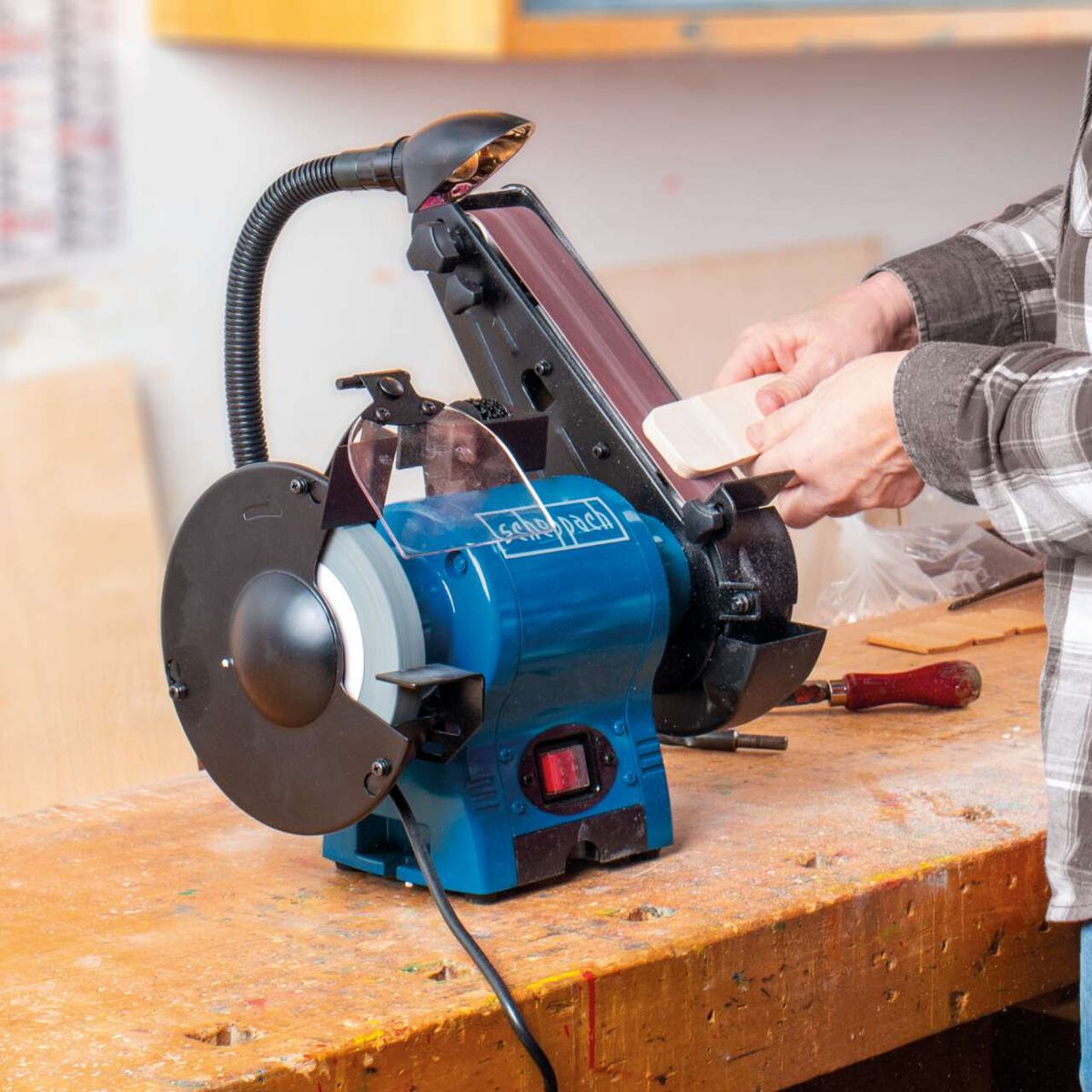 Scheppach combination grinder with grinding belt in use on workpiece