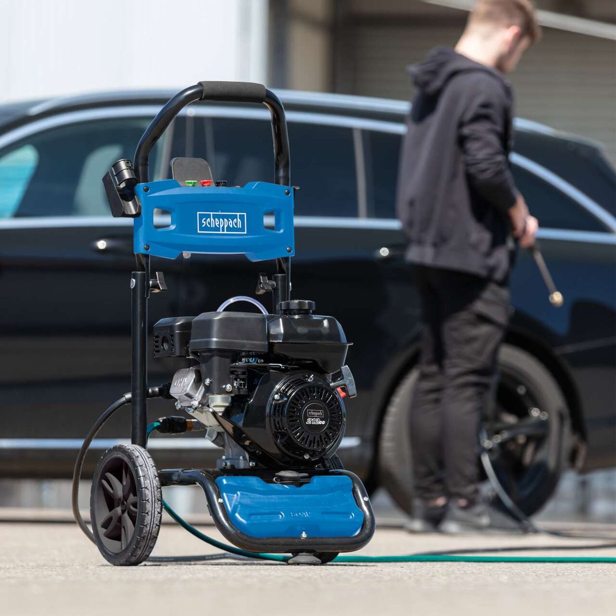Scheppach high-pressure cleaner with engine and hose holder, being used outdoors