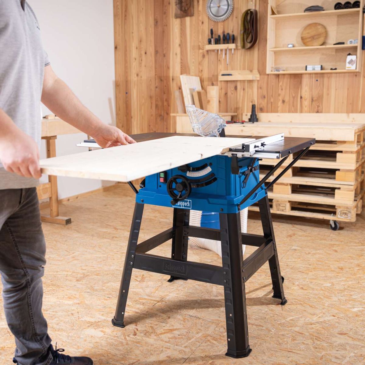Scheppach table saw with worktop, being operated by a person placing a wooden board on it