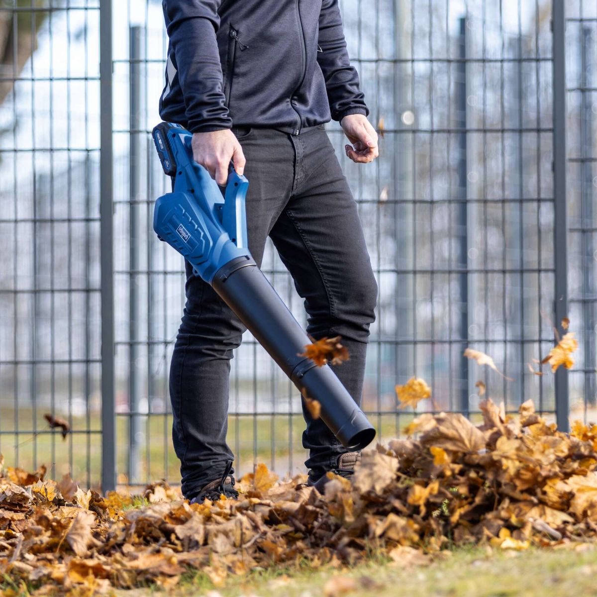 Person using a Scheppach cordless leaf blower with leaf collection attachment