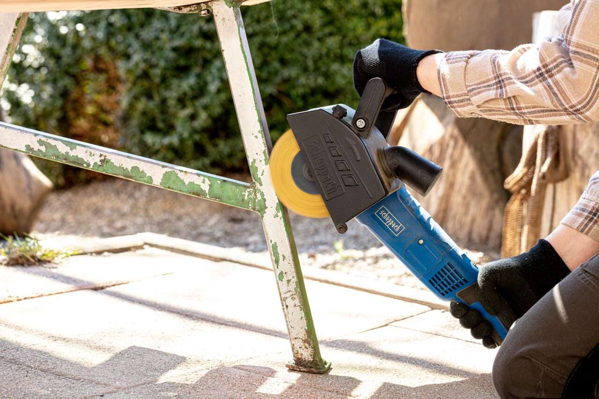 Person operating a Scheppach wire brush on metal piece with black handle