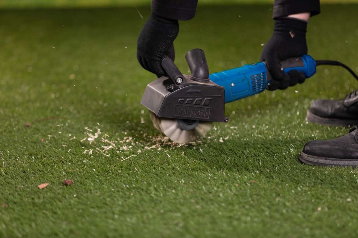 Scheppach plastic fiber brush in use on grass surface