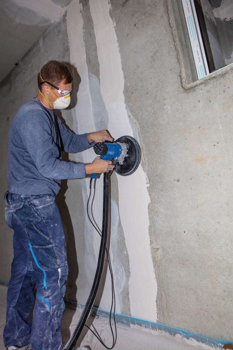 Person sanding wall surface with Scheppach wall and ceiling sander (DS200) inside