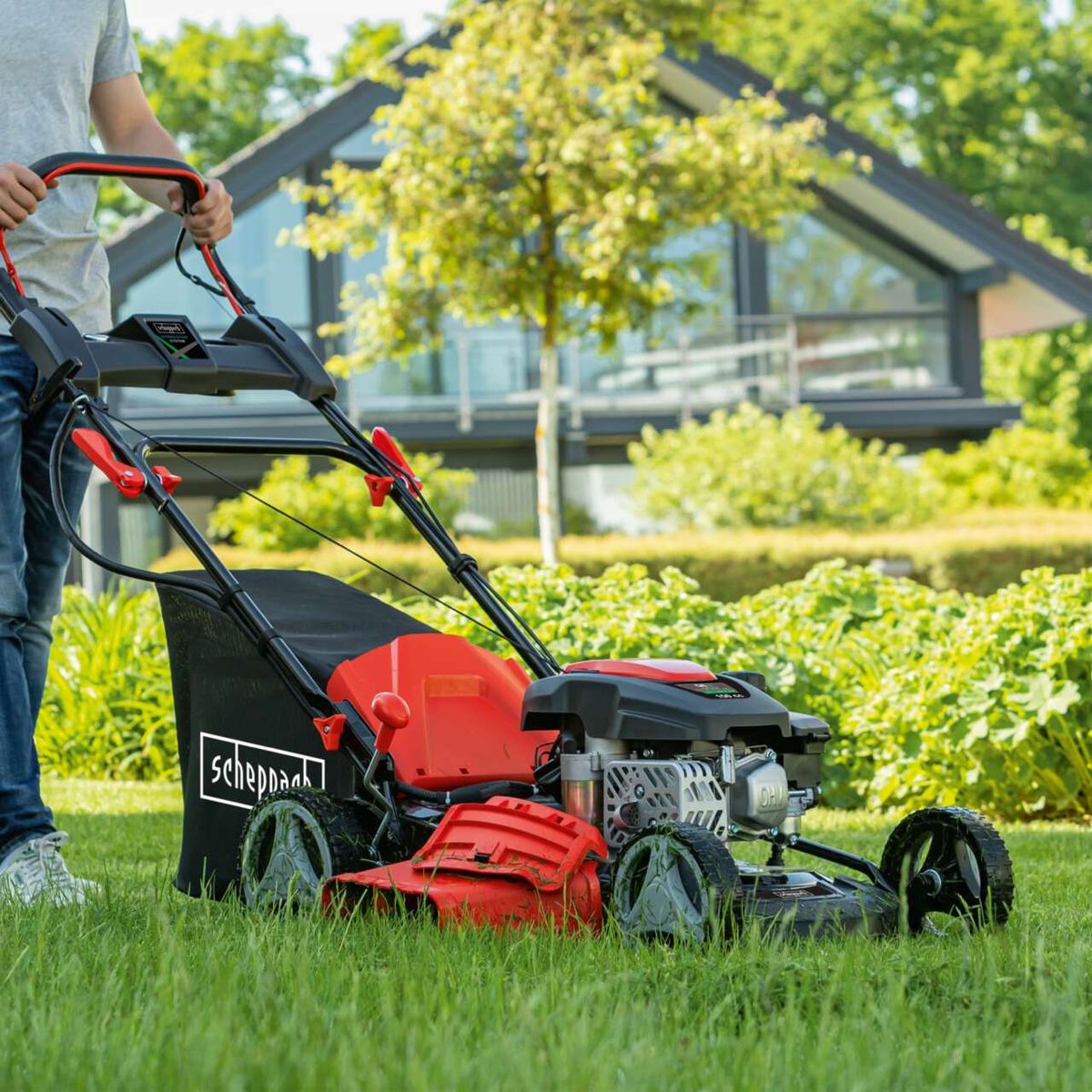 Scheppach petrol lawnmower MS150-46E with handle and engine attachment, being used on grass