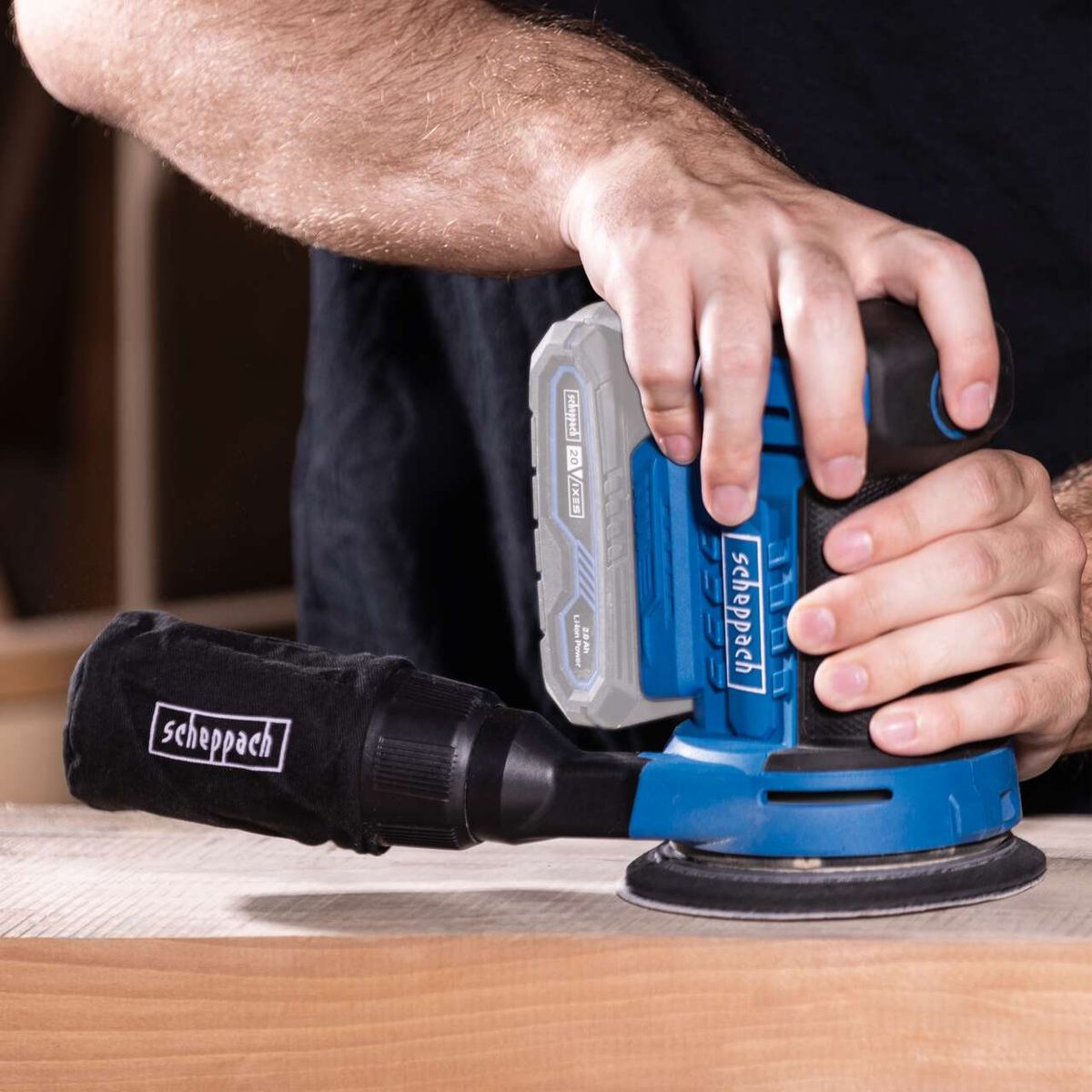 Scheppach cordless orbital sander with attached disc and grip, close-up of operation