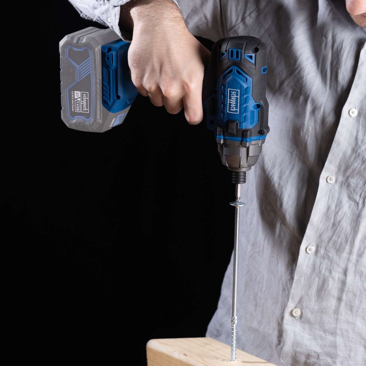 Cordless impact driver in use, driving a screw into wood