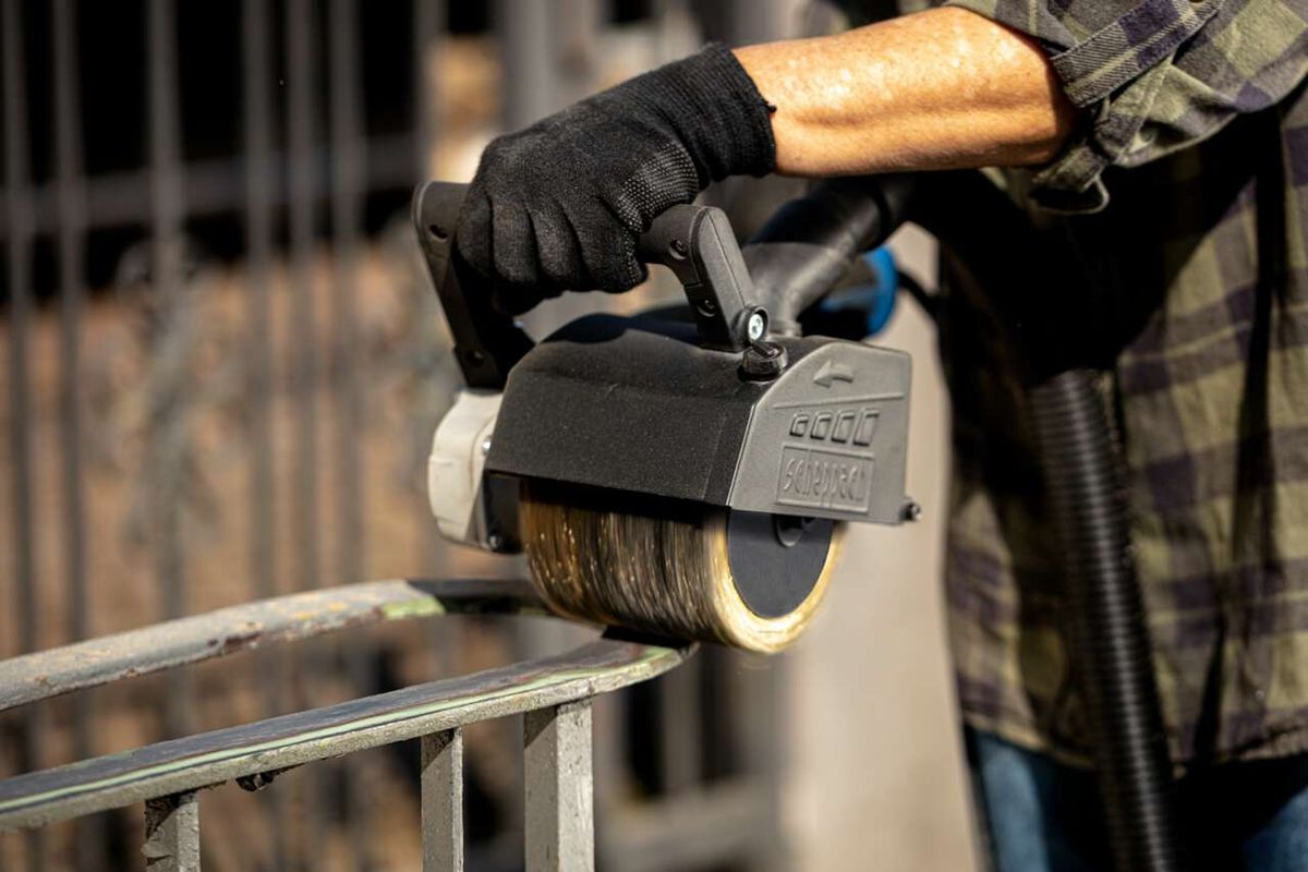 Scheppach metal wire brush in use on a machine. The brush is operating and being held by a person.
