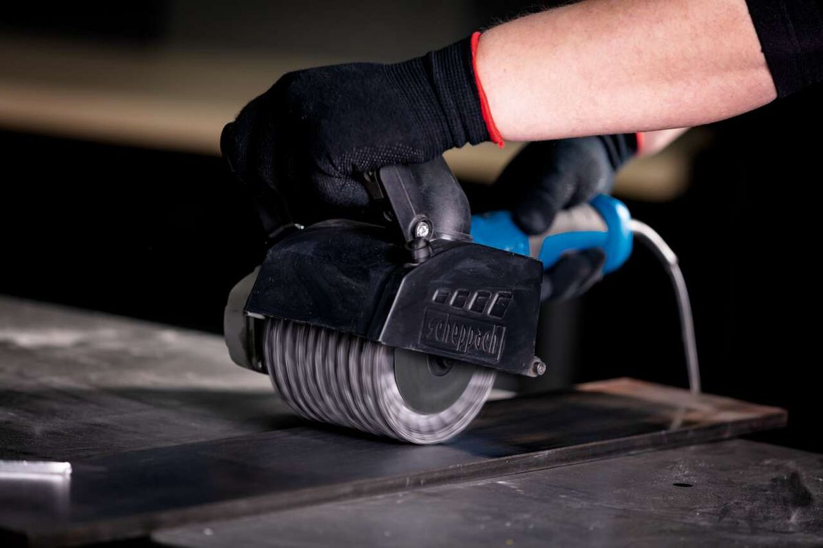 Scheppach metal wire brush with handle, close-up of operation on a workpiece