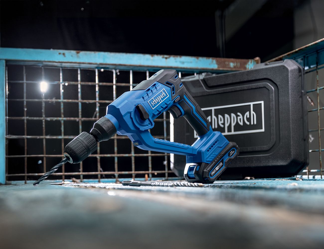 Scheppach cordless drill in a tool case. The drill is blue and black and is placed on a blue background. In the background, there is a tool case with the Scheppach logo.