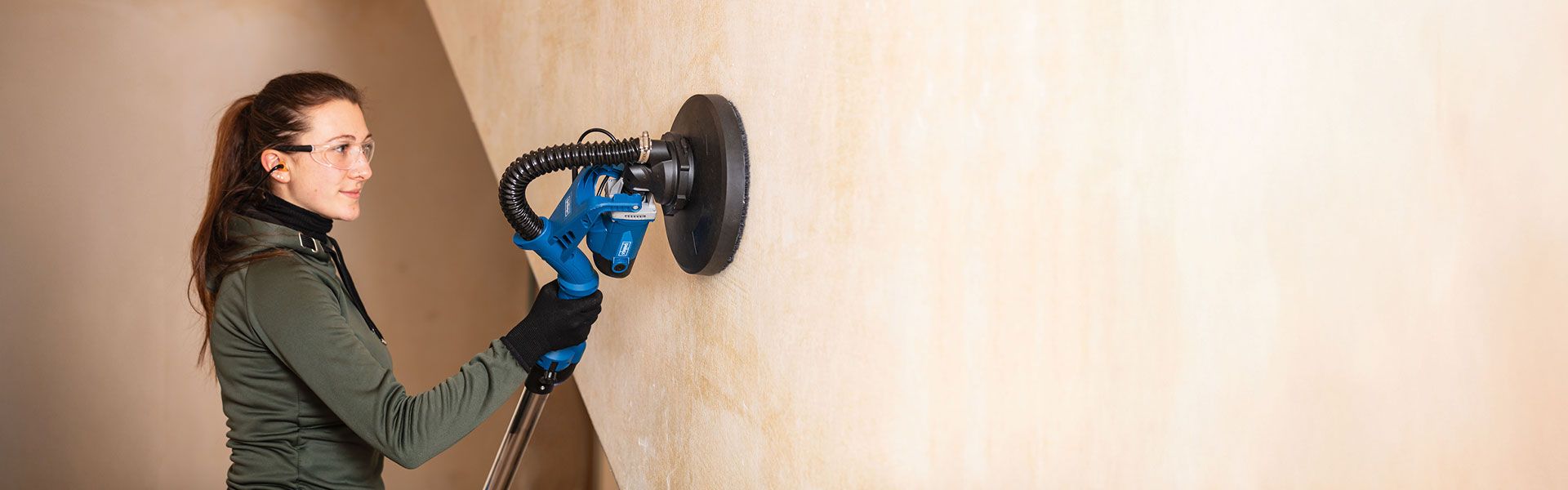 Woman sanding or smoothing a wall with Scheppach tool